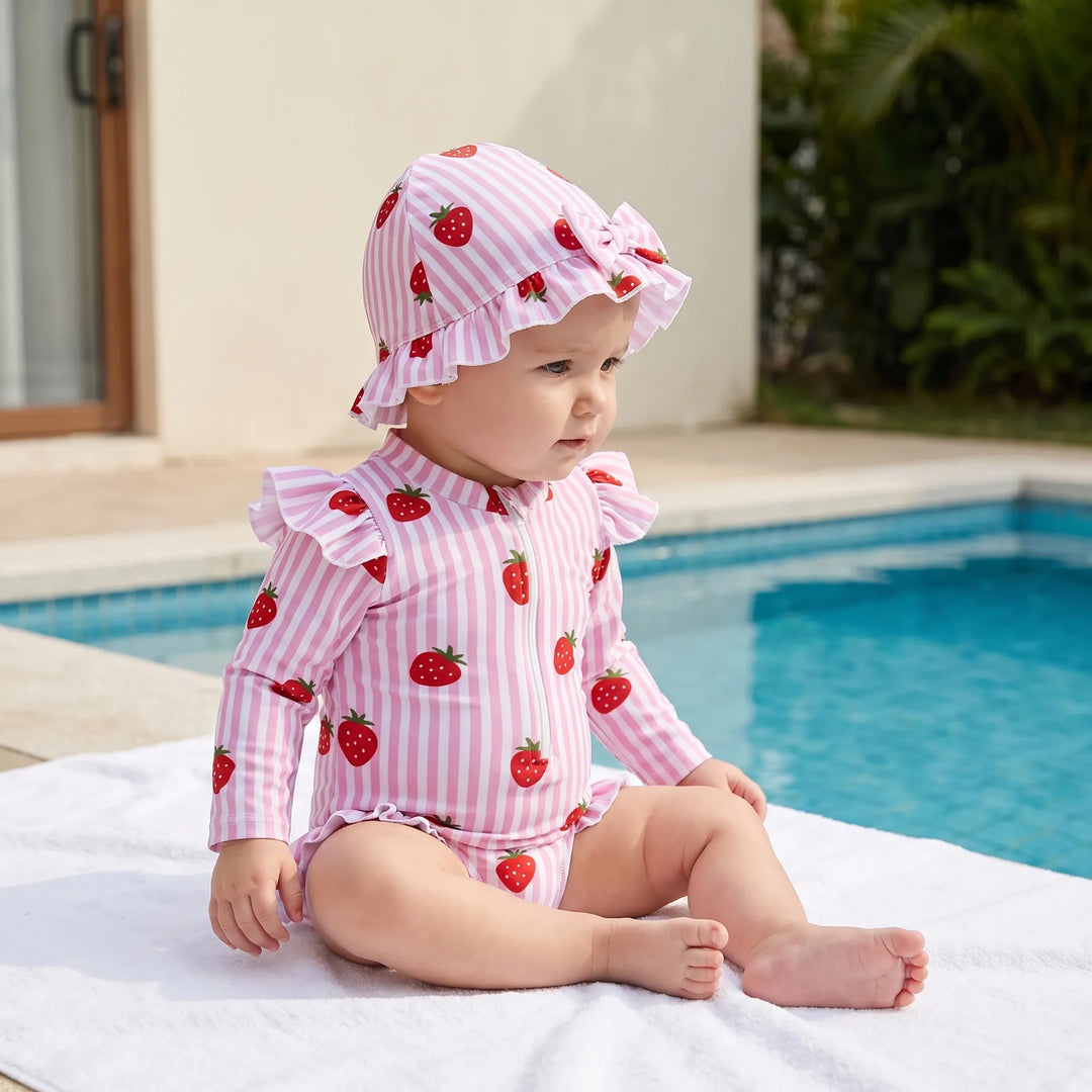 Toddler girls' long-sleeve rashguard swimsuit with matching sun hat, offering UPF sun protection for beach play.