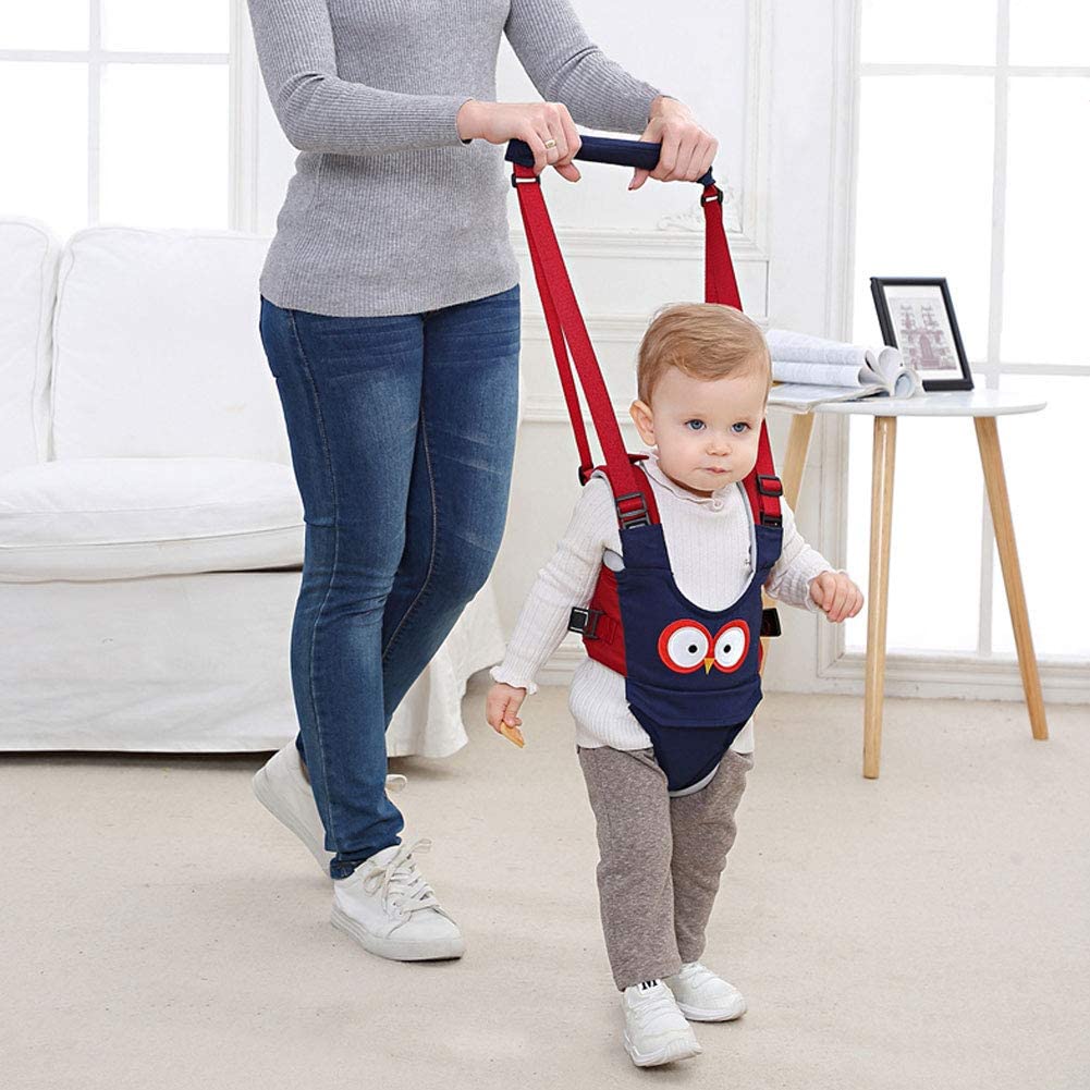 Toddler in a blue walking harness, learning to walk with parent support, a safe baby walking aid.