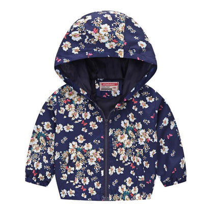Toddler girl smiling in a vibrant floral hooded windbreaker jacket, cozy and playful fall clothing.