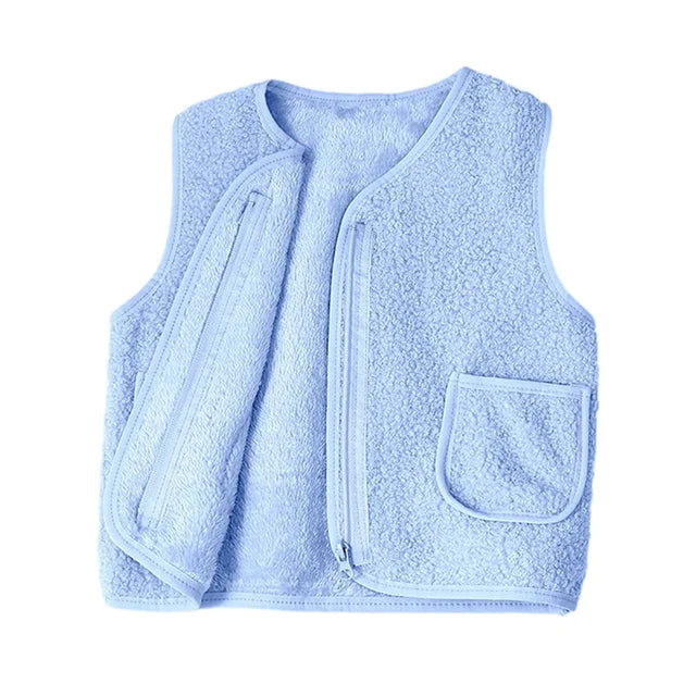 Arrangement of a lambswool vest with other kids' winter clothing, highlighting its role as a layering piece.