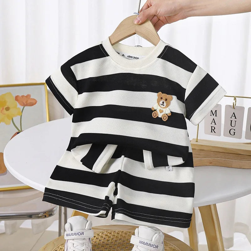Toddler in blue and white striped t-shirt & shorts set playing on grass, comfortable cotton blend.