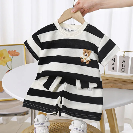 Toddler in blue and white striped t-shirt & shorts set playing on grass, comfortable cotton blend.