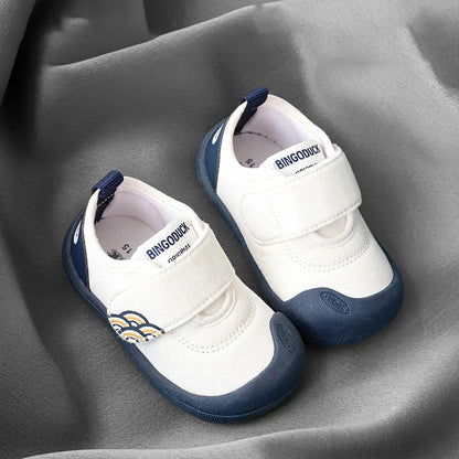Child sitting, putting on their own blue breathable canvas sneakers, demonstrating easy wear.