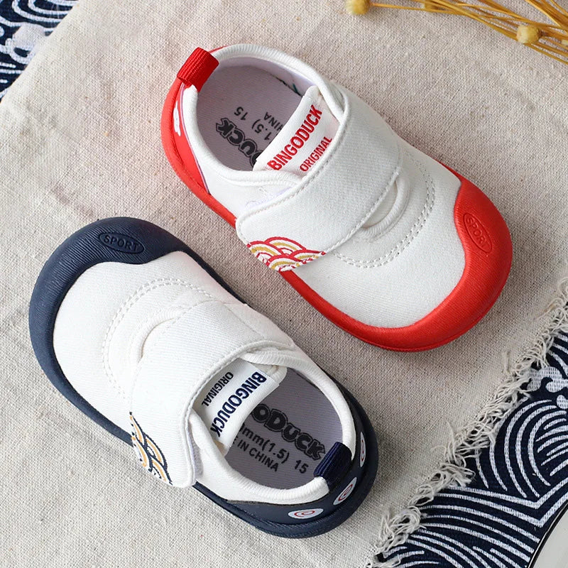 Side view of a red canvas toddler shoe, highlighting its flexible design for comfortable movement.