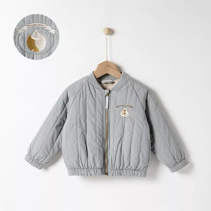Child smiling while wearing a pink cotton padded winter jacket. Cozy and stylish toddler outerwear.