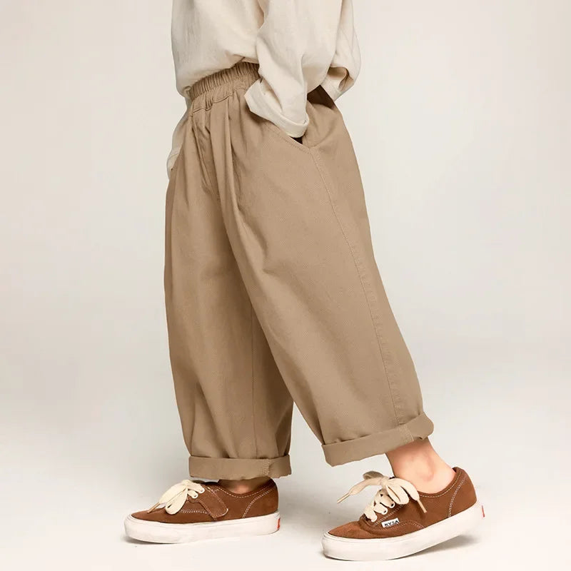 Young child wearing mustard yellow wide leg cotton pants, casual fall fashion, playing in leaves
