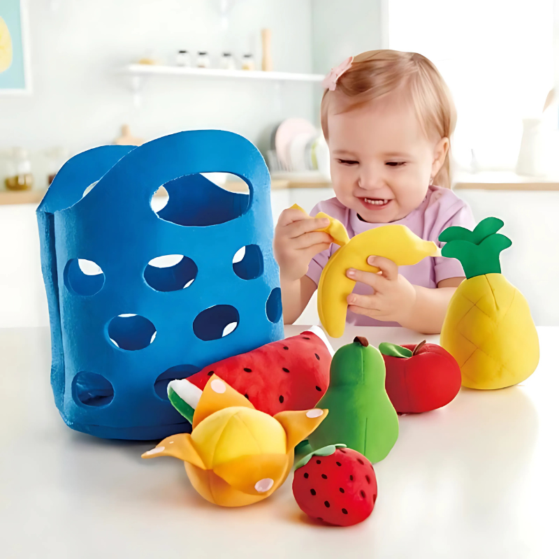 Toddler playing with felt market basket, holding vibrant felt vegetables & fruits from the learning toy set.