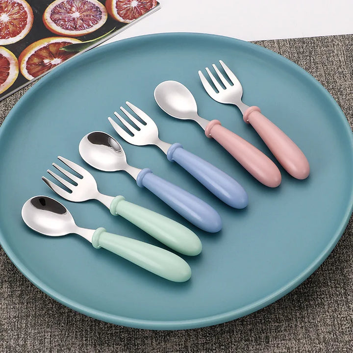 Toddler eating happily with a green cartoon stainless steel dinnerware set. Child-safe baby feeding solution.