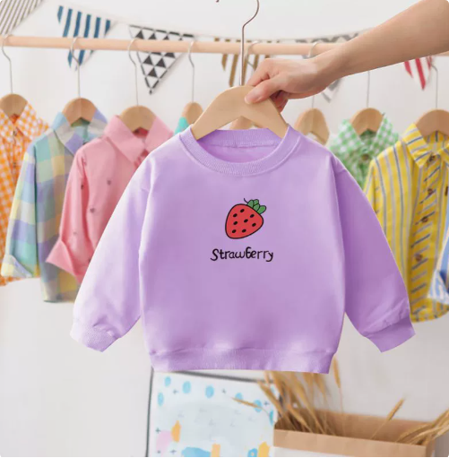 Flat lay of a unisex toddler's cotton strawberry sweater on a wooden background