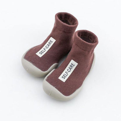 Detail of the non-slip grip on the sole of a toddler's soft sock shoe, safety first