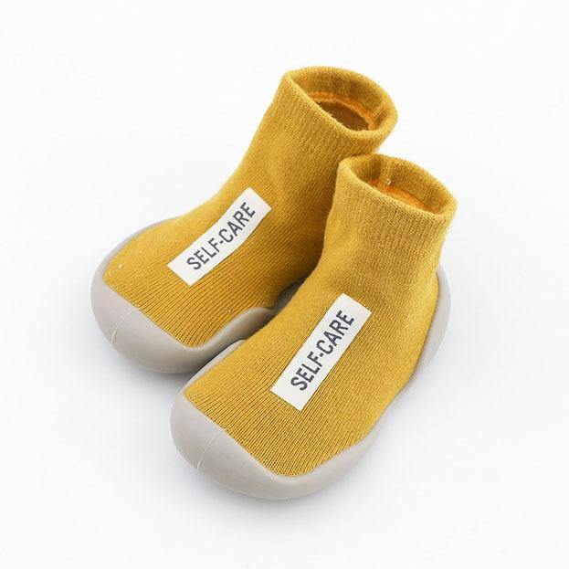 Toddler sitting down, showcasing their comfortable grey indoor sock shoes for all-day wear