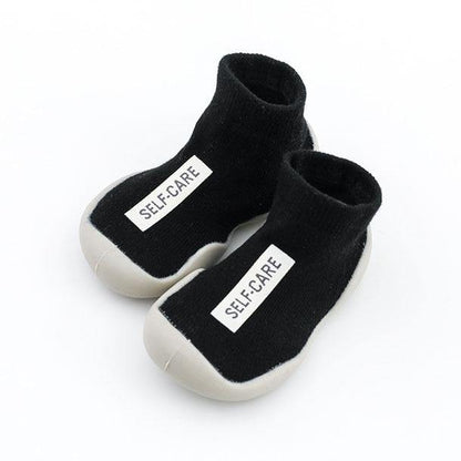 Front view of black soft-sole baby sock shoes, providing warmth and protection indoors