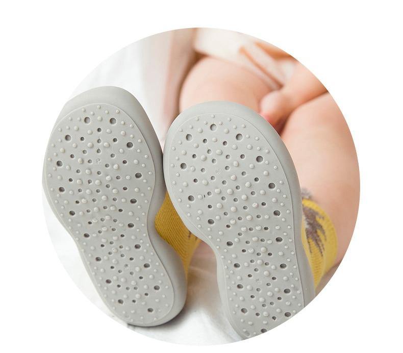 Toddler's first steps assisted by comfy cotton blend indoor sock shoes in a neutral shade