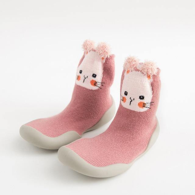 Baby wearing striped sock shoes, showing the flexible soft sole for easy crawling & walking