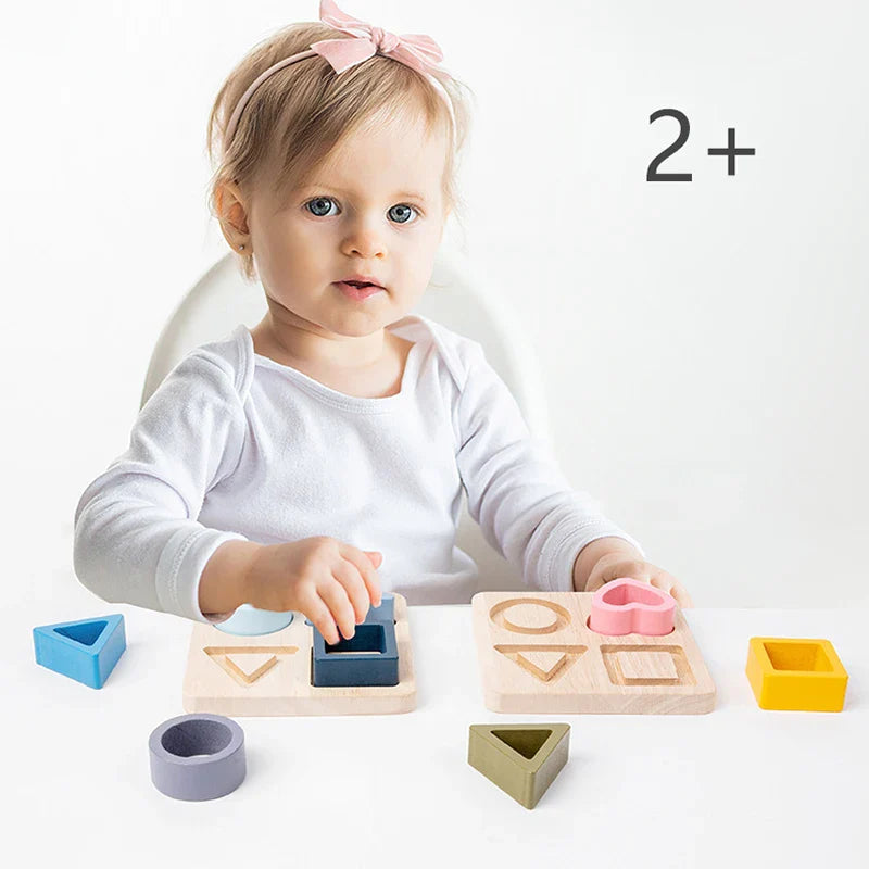 Close-up of a toddler's hand placing a blue silicone triangle into a geometric shape sorter toy
