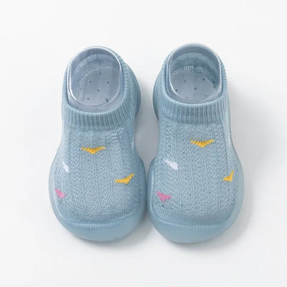 Overhead shot of two pairs of non-slip toddler walking shoes, blue and pink, soft sole.