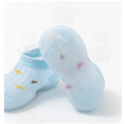 A child's hand holding a grey soft sole non-slip toddler walking shoe, infant footwear.