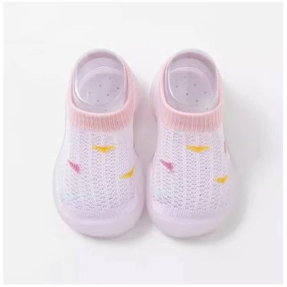 Infant footwear: yellow soft sole non-slip walking shoes on a wooden floor.
