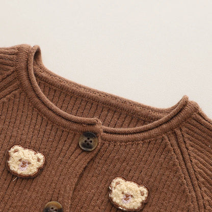 Full view of a toddler wearing a bear-themed winter sweater and matching comfy pants
