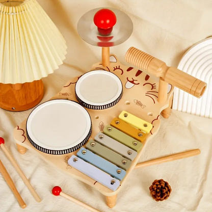 Close-up of a toddler's hand playing the colorful wooden xylophone, part of a drum set toy.