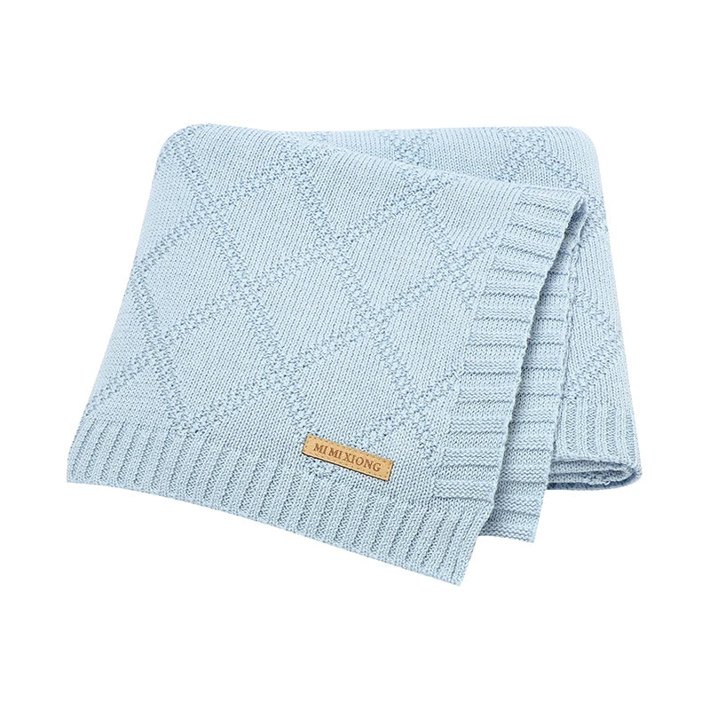 Baby gently sleeping in a pale blue cotton swaddle, a soft and essential newborn item