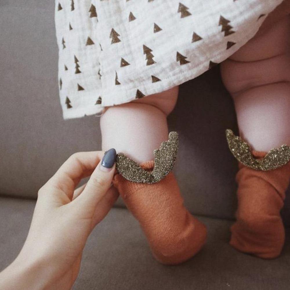 Close-up of white baby anti-slip socks with delicate angel wings for toddlers