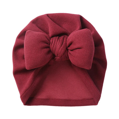 Adorable baby topknot bonnet with a decorative bow, made from soft cashmere-like fabric