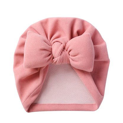 Side profile of an infant wearing a cozy cashmere style bow topknot bonnet