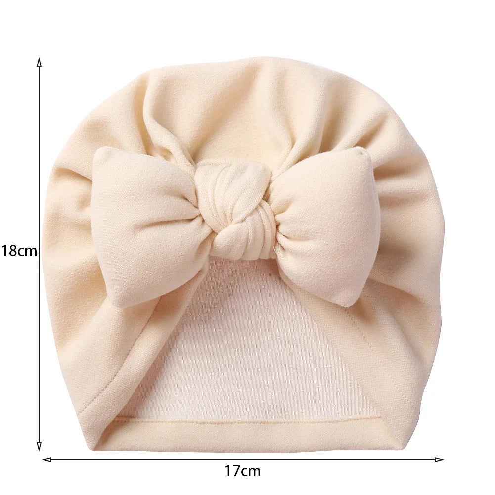 Close-up of cashmere-like bow topknot bonnet for baby, cozy newborn headwear in neutral color