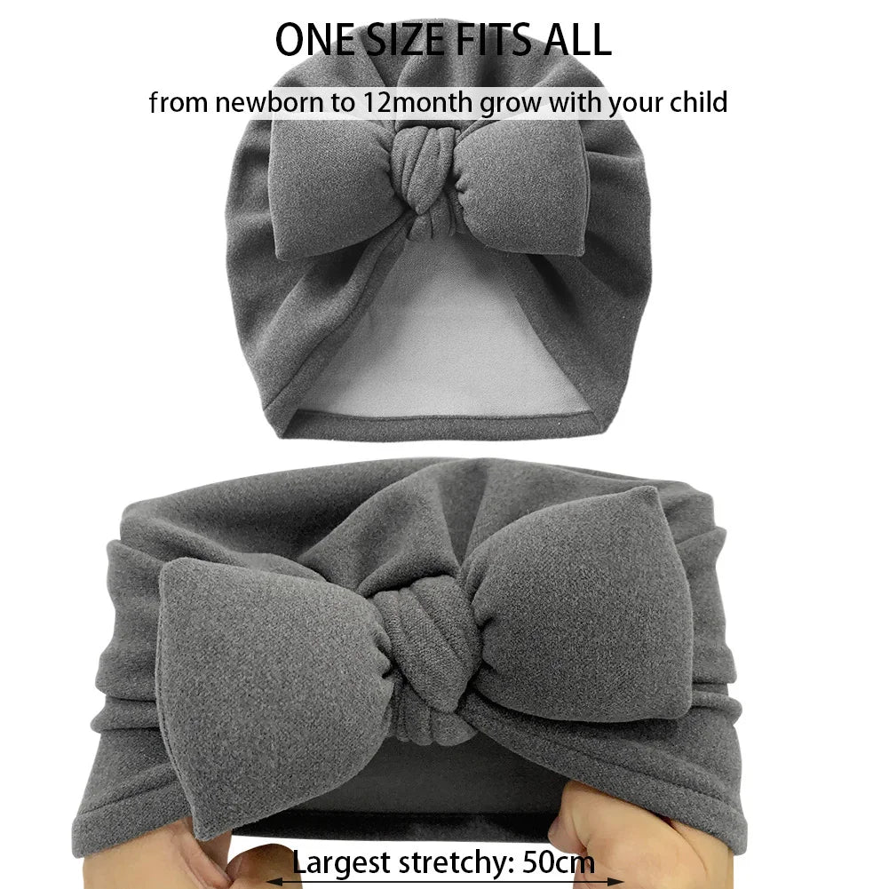 Baby wearing a warm unisex cashmere-like topknot bonnet with a cute bow accent