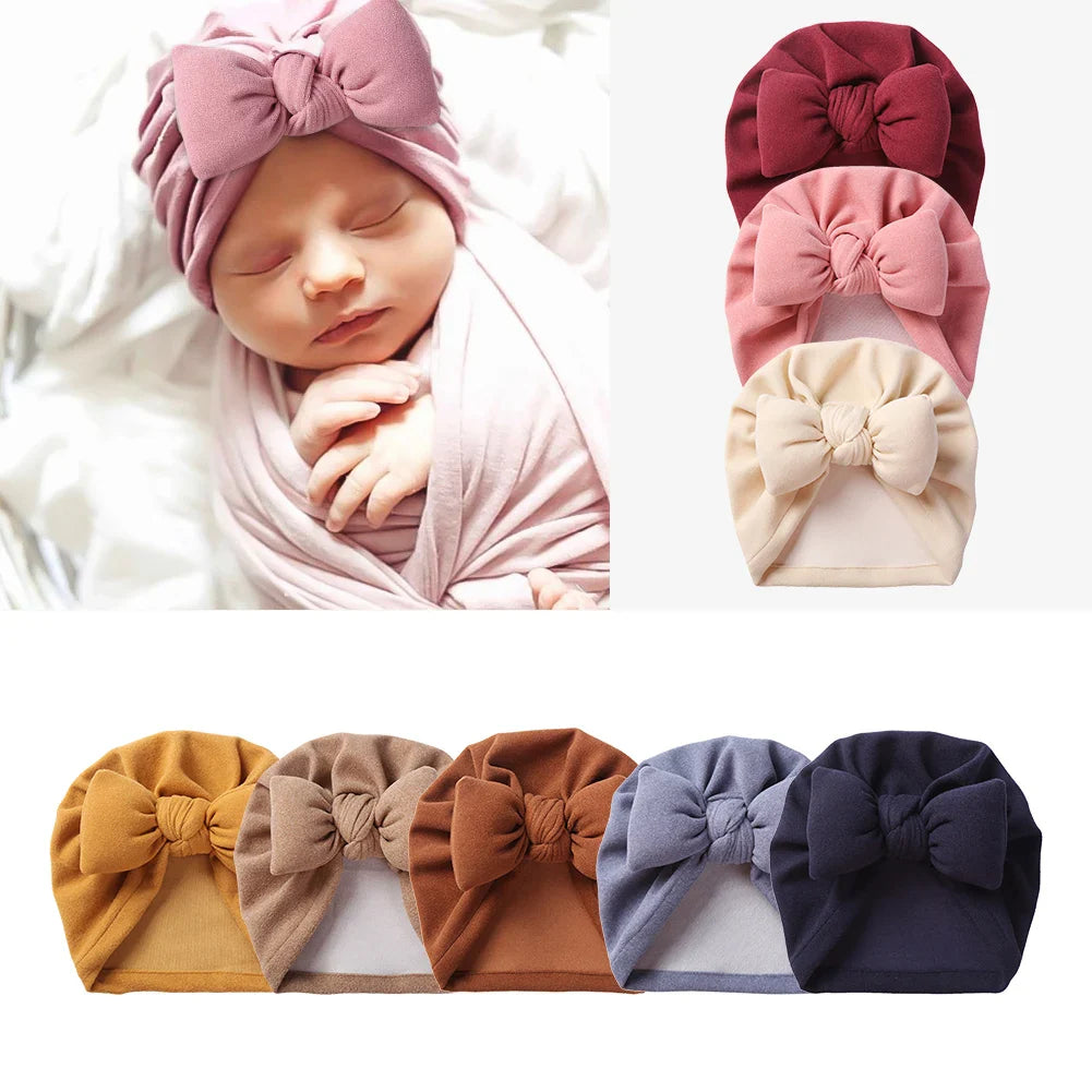 Delicate cashmere-like baby hat with a prominent front bow and topknot style