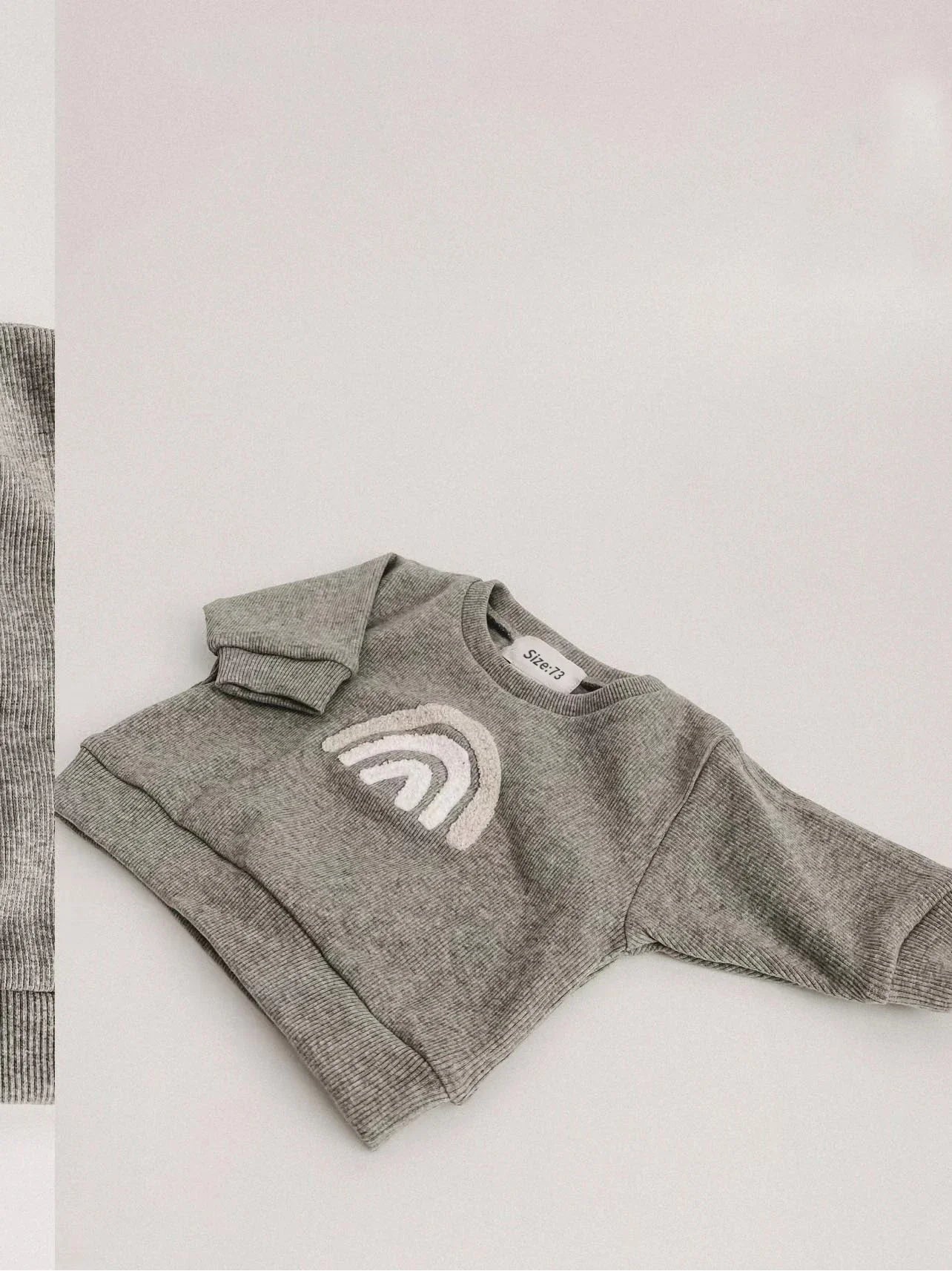 Flat lay of infant unisex ribbed cotton top and pants, highlighting the soft knit and easy wear design