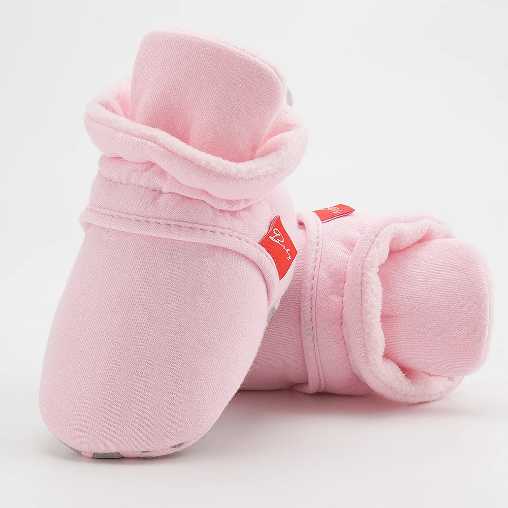 Side view of a baby's foot in a cotton soft sole first walker sock shoe.