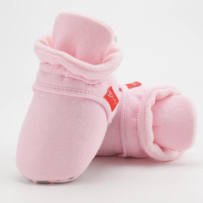 Side view of a baby's foot in a cotton soft sole first walker sock shoe.