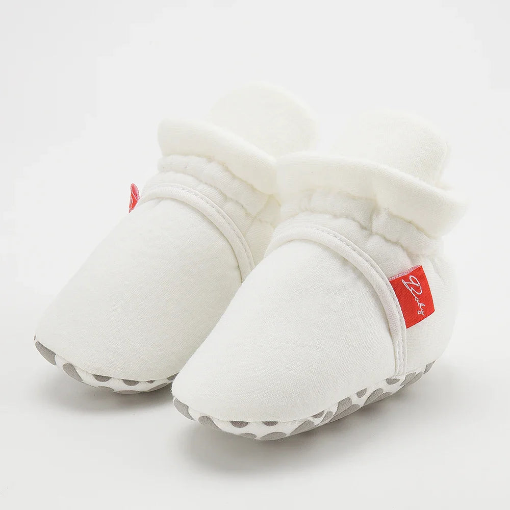 Group of unisex baby first walker sock shoes, different colors and patterns.
