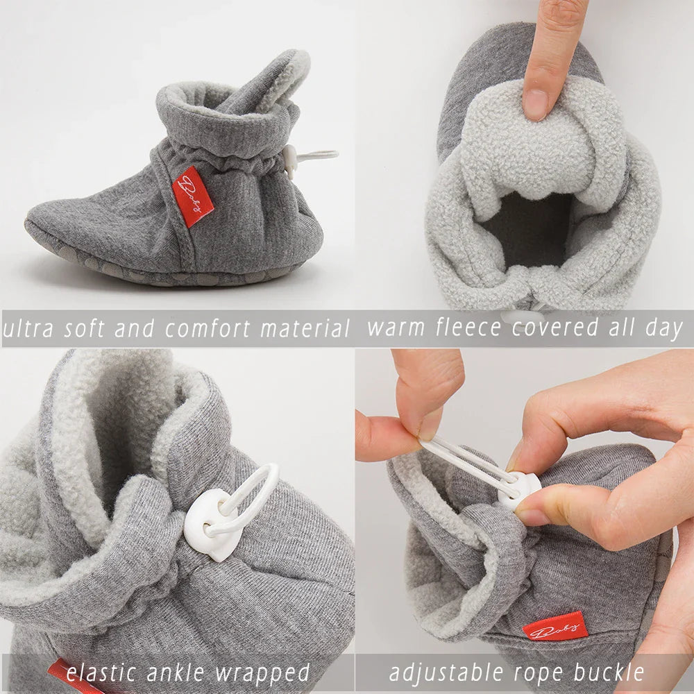 Baby wearing black unisex cotton soft sole first walker sock shoes, sitting.