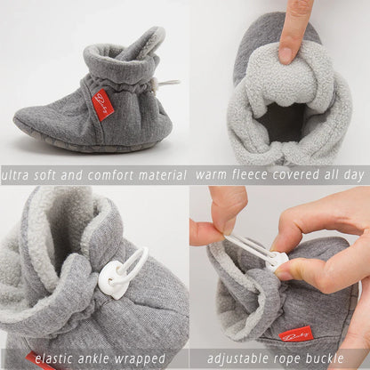 Baby wearing black unisex cotton soft sole first walker sock shoes, sitting.
