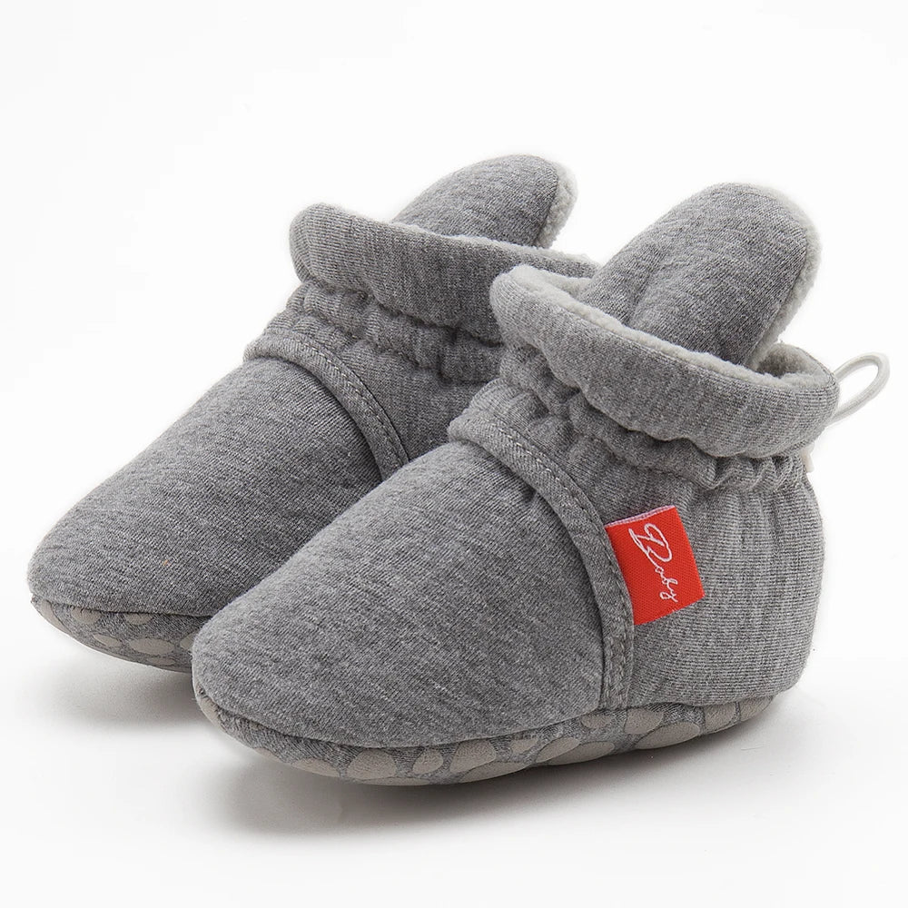 Toddler taking first steps in comfortable unisex baby cotton soft sole sock shoes.