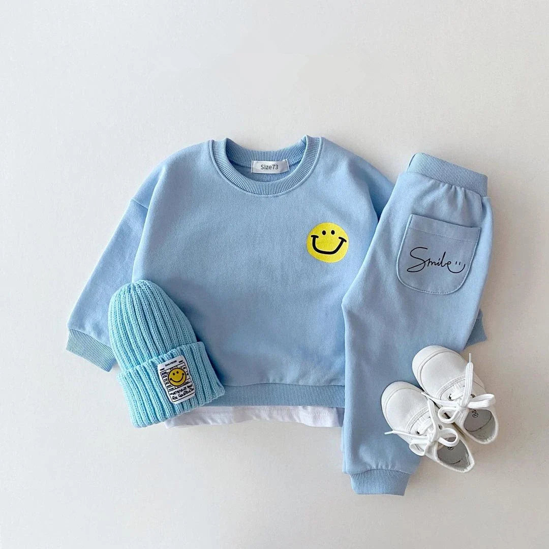 A cozy yellow cotton tracksuit set for baby with cute smiley face detail, suitable for autumn weather.
