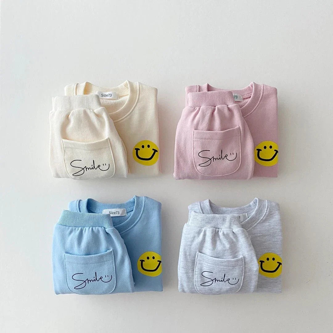 Back view of a unisex baby yellow cotton tracksuit set featuring a large smiley face, comfortable jogger set.