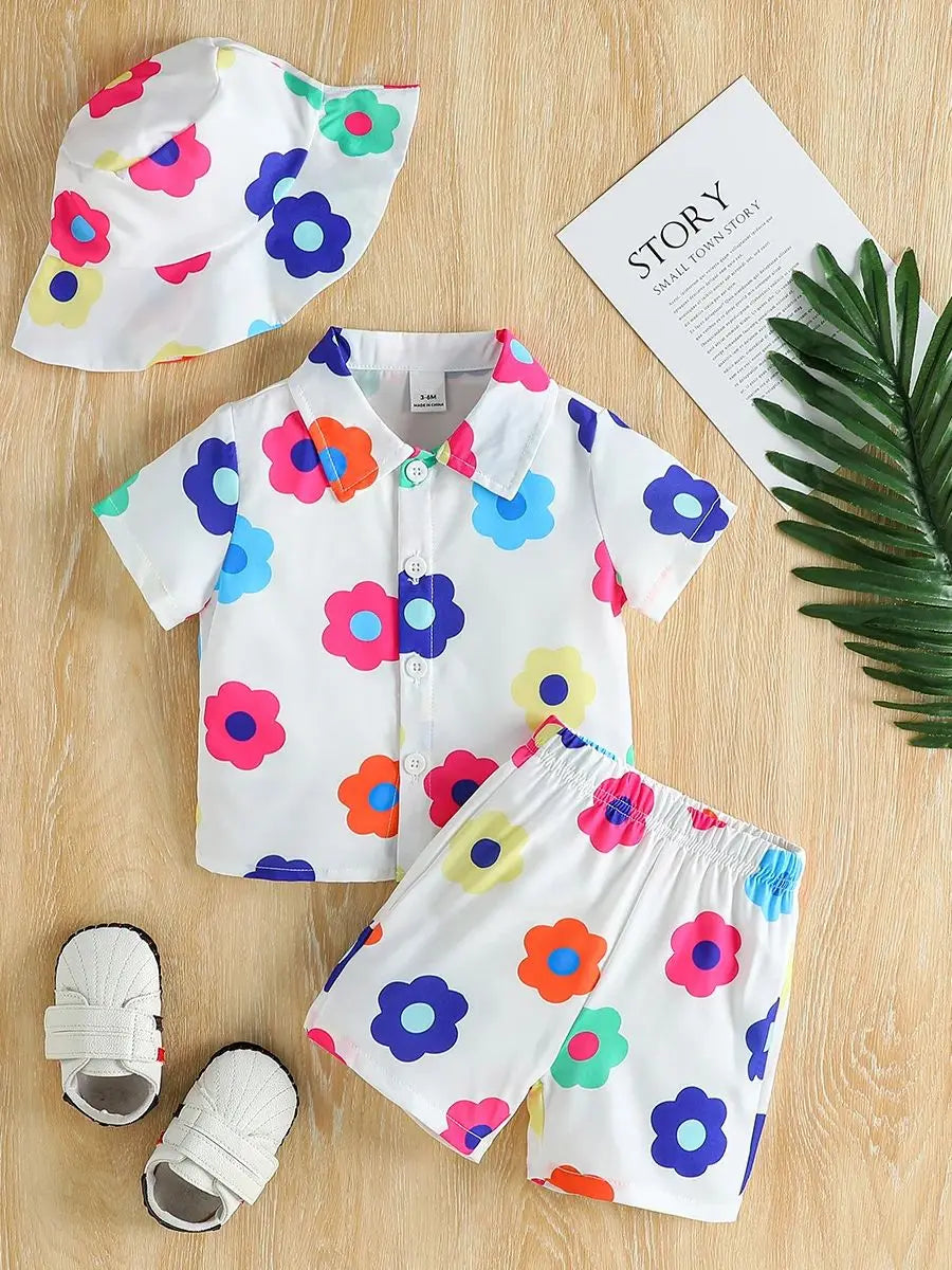 Flat lay of the complete unisex baby floral summer outfit set including romper, shorts, and hat
