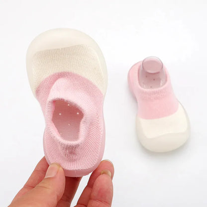 Baby's joyful expression wearing soft knit walking boots