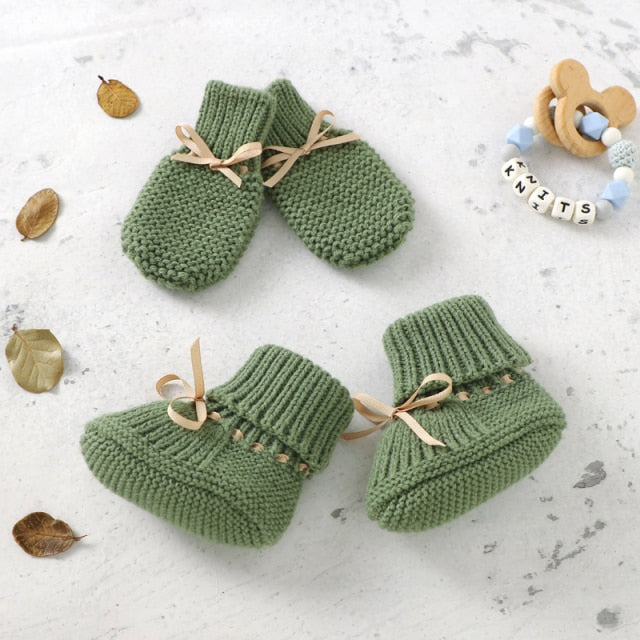 Newborn wearing white knitted baby booties and mittens set, cozy, soft knit, anti-slip infant shoes