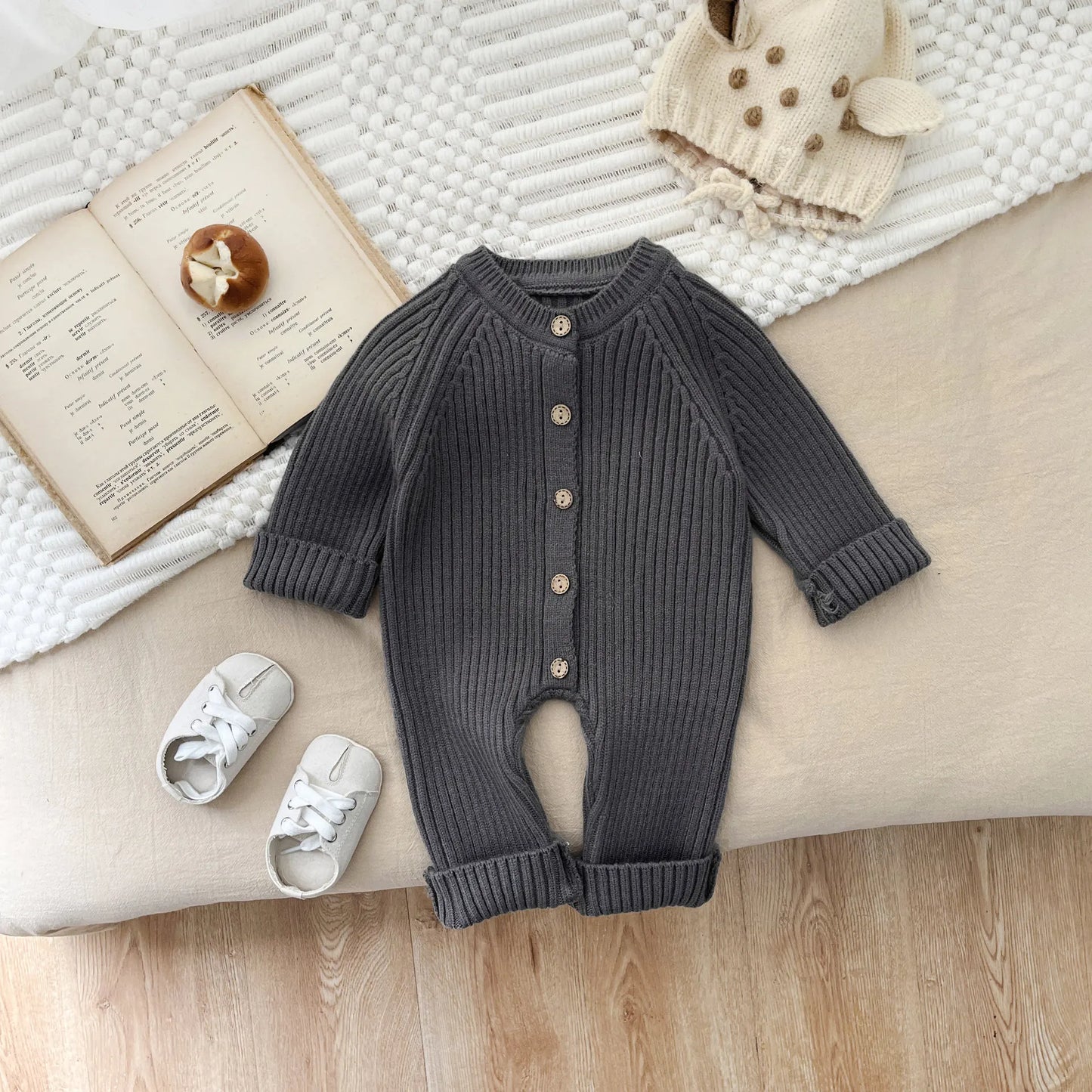 Knitted romper for baby, featuring long sleeves and a soft cotton blend for comfort