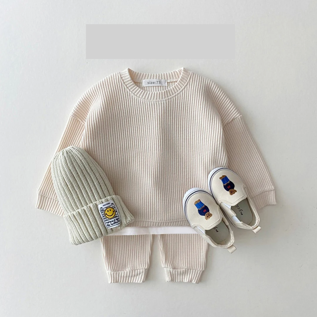 👶 Stack of folded unisex baby cotton long sleeve bodysuits, organized infant apparel