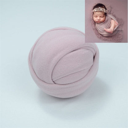 Newborn baby wrapped comfortably in a neutral stretchable cotton blend blanket for photos