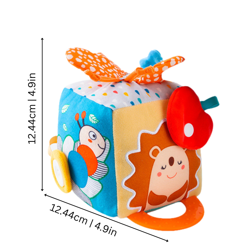 Infant exploring soft sensory cube with various tags & colors for early education, promoting developmental skills.