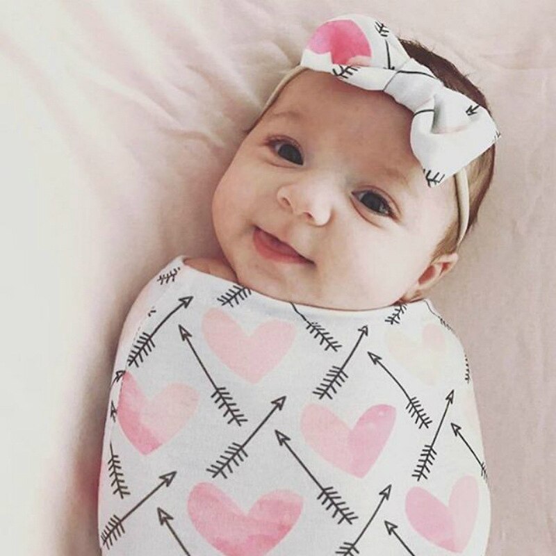 Infant swaddle sleeping bag in a neutral color, paired with a matching baby headband.