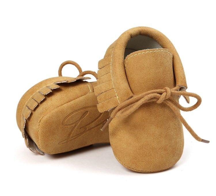 Toddler wearing unisex baby moccasins, first walker shoes with anti-slip grip and tassel detail.