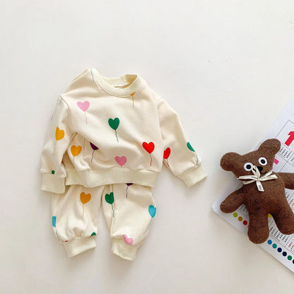 Close-up of soft cotton baby tracksuit showing detailed heart print and fabric texture.